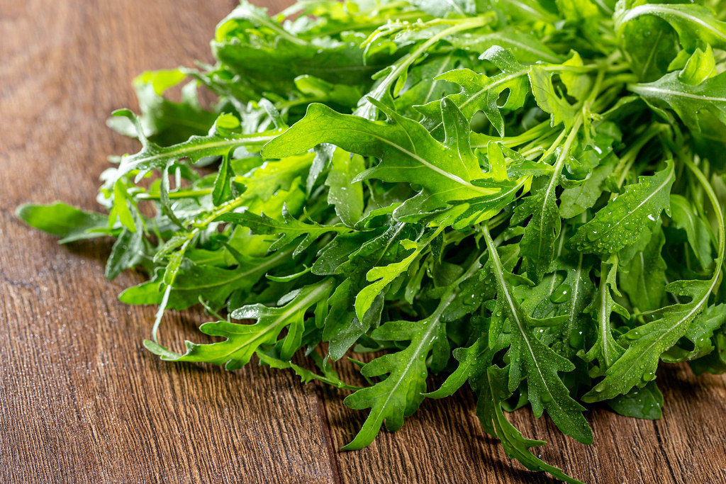 Fresh arugula on brown wooden background close-up