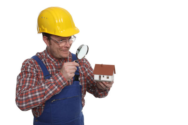 Bauarbeiter mit Lupe und Modellhaus