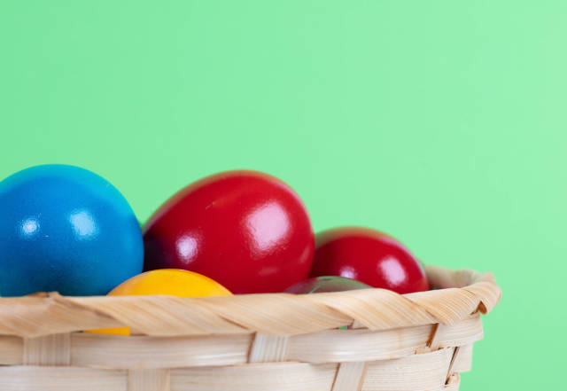 Easter eggs in a basket on green background