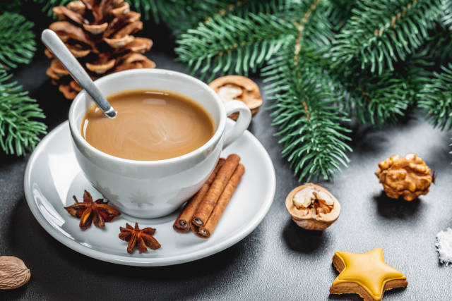 Christmas composition of coffee with gingerbread, Christmas tree branches and New Year spices on a dark background