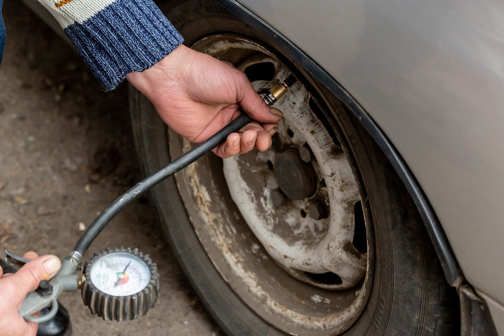 Man checking air pressure and filling air in the tires of his car