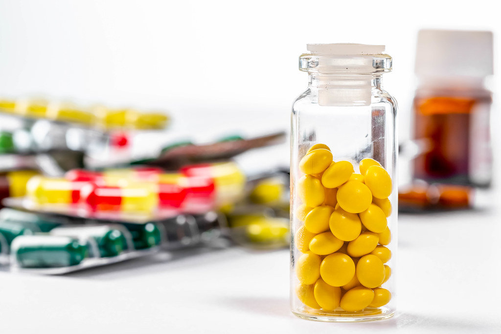 Tablets in a glass bottle and blisters on a white background