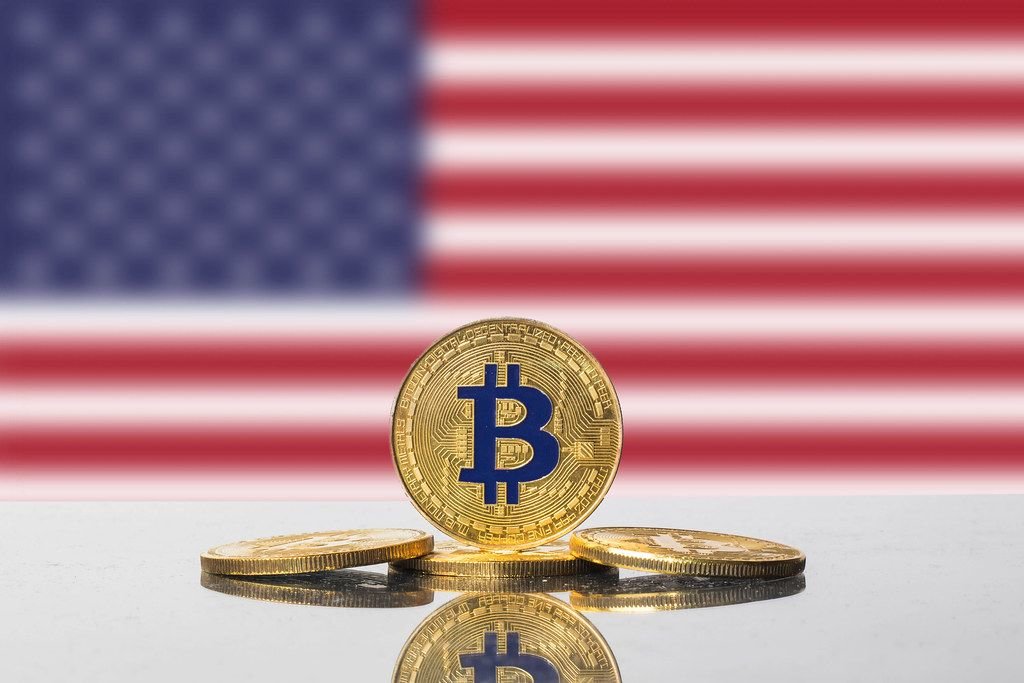Vier goldene Bitcoins vor amerikanischer Flagge repräsentieren Kryptowährungen in den USA
