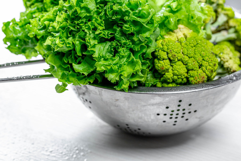 Wet lettuce and broccoli in a sieve
