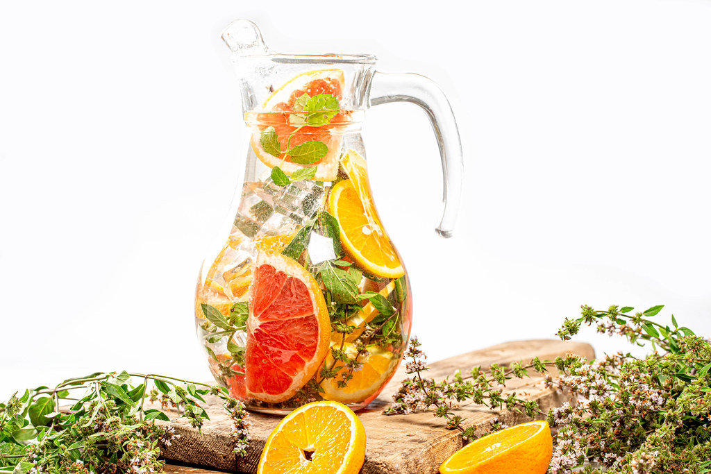 Glass jug with ice cubes, fresh mint, and citrus slices