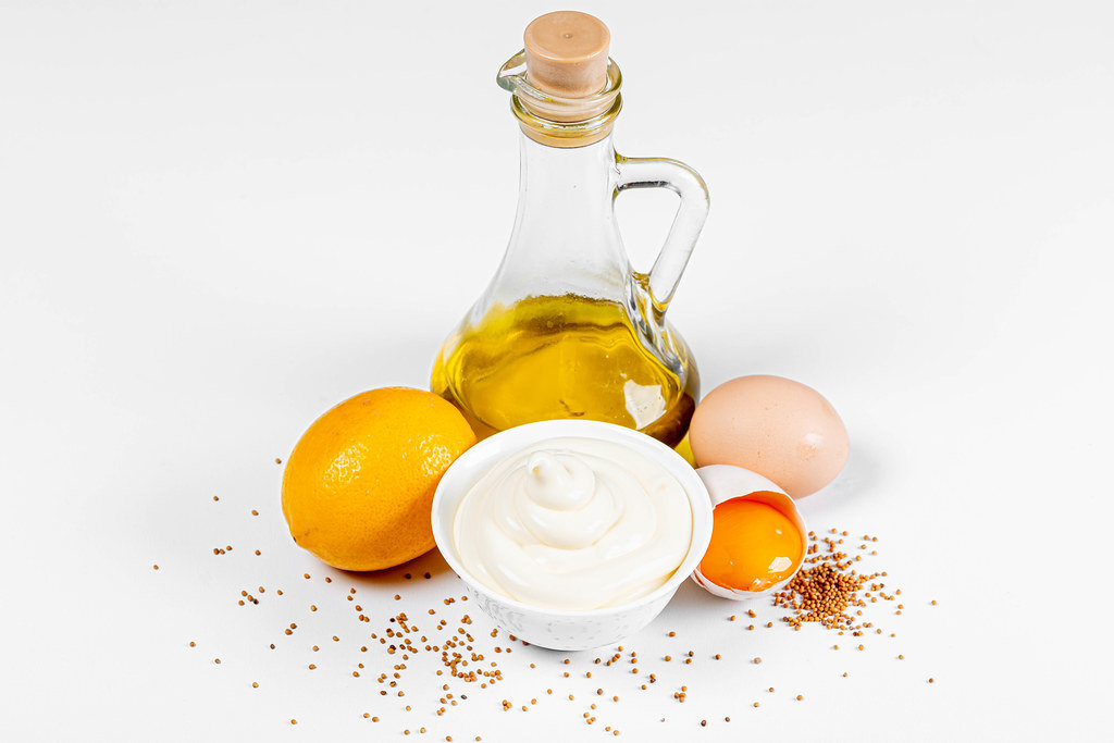 Fresh mayonnaise with ingredients on a white background