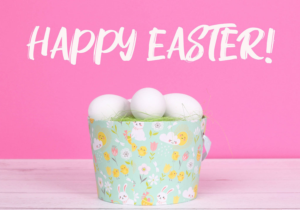 Easter eggs in a basket with pink background and Happy Easter text