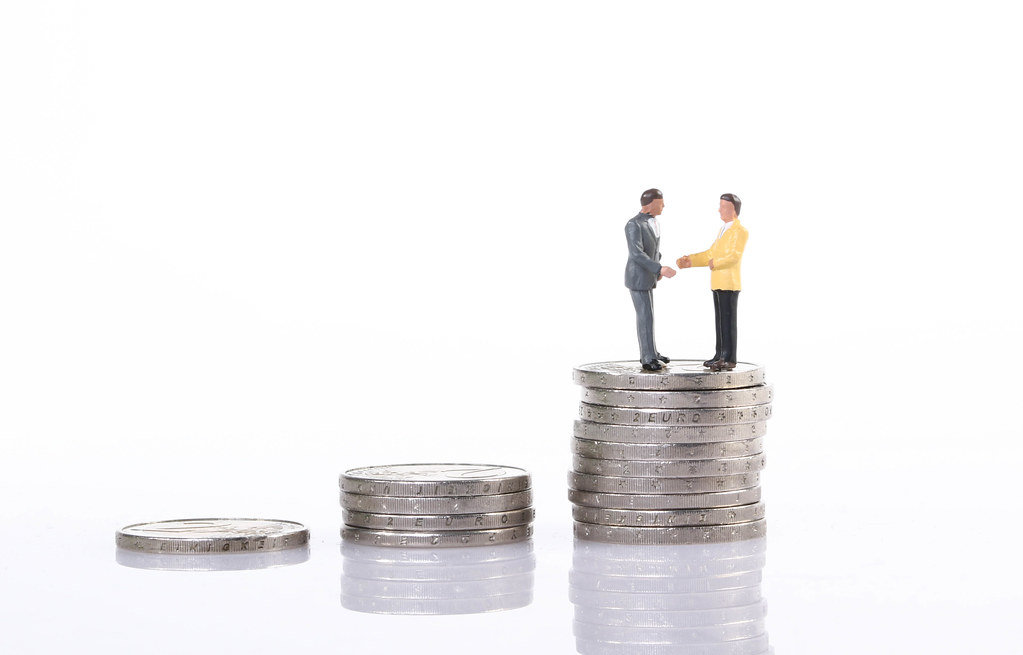 Businessman handshake on top of coin stacks