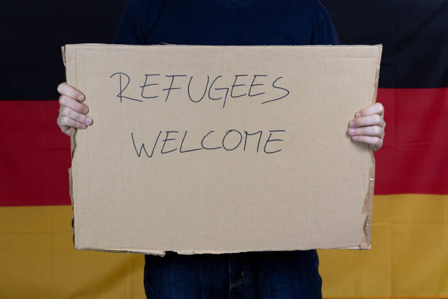 Man holding refugees welcome sign