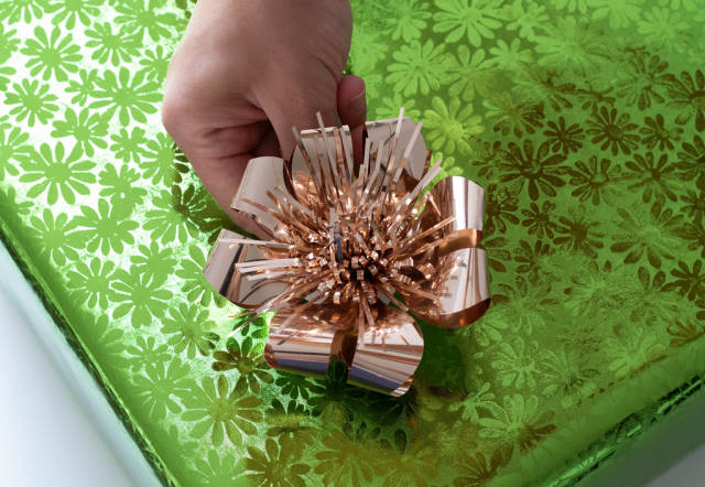 Closeup image of girls hands putting bow to  gift