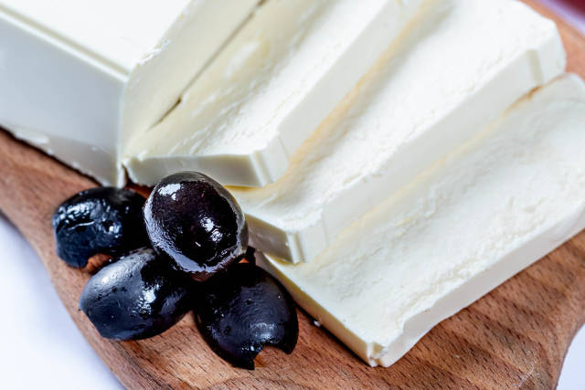 Feta cheese with olives on wooden board