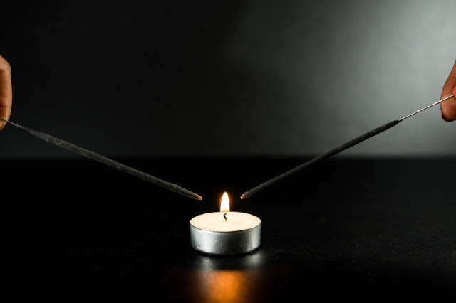 Two sparklers close to a candle flame