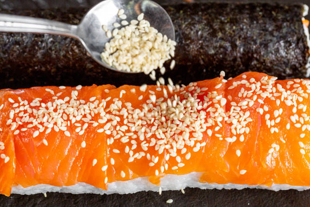 Close-up of sesame pours on sushi roll with salmon