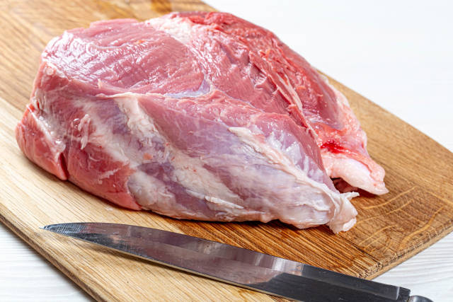 A large raw piece of pork with a knife