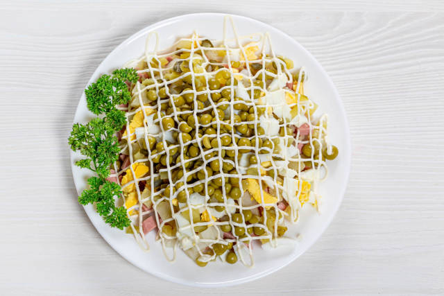 Olivier salad on a white wooden background. The view from the top