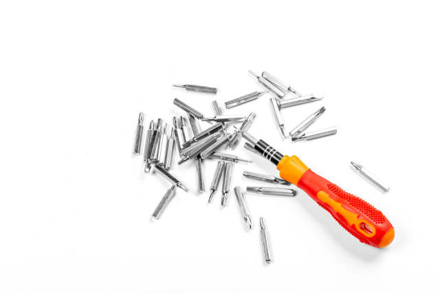 Red screwdriver with different attachments on a white background