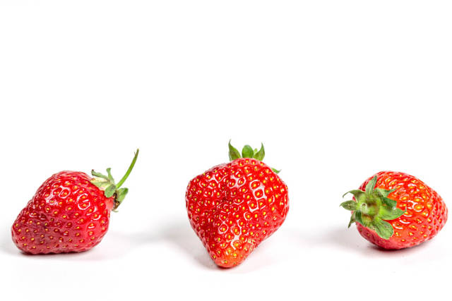 Three ripe strawberries on a white background