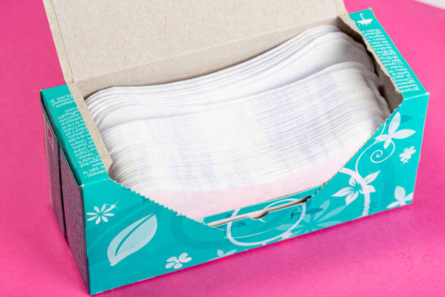 Womens daily pads in an open package on a pink background
