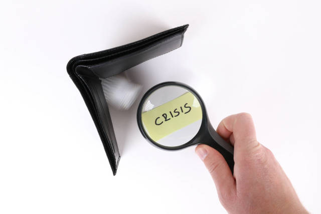 Crisis text under magnifying glass with wallet on white table
