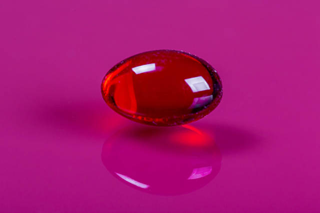 Red capsule on pink background. Medical healp concept