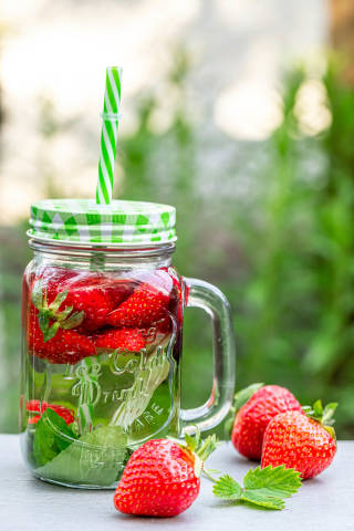 Strawberry drink in a glass jar on a blurred background of nature
