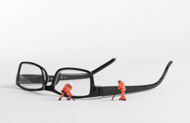 Miniature technician repairing reading glasses