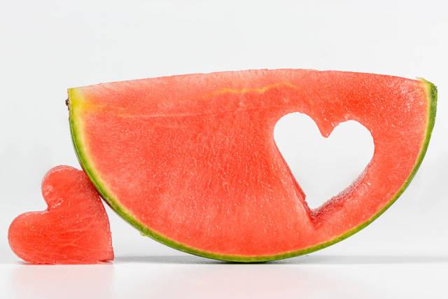 A slice of ripe watermelon with a carved heart