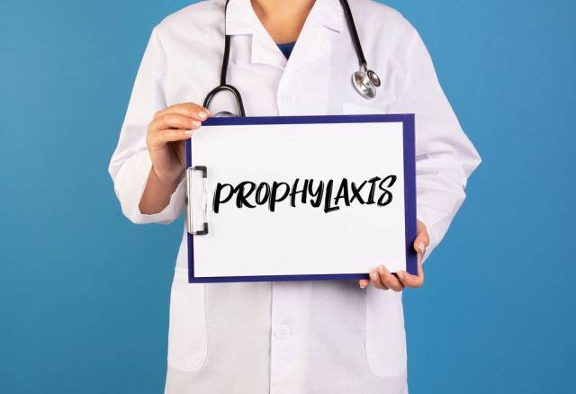 Arzt hält einen Schild mit der Schrift Prophylaxis im blauen Hintergrund