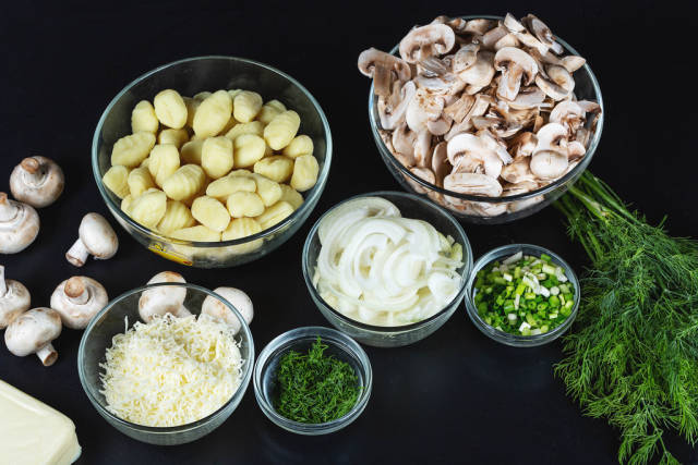 Ingredients for making potato gnocchi with mushrooms and cheese on a black background