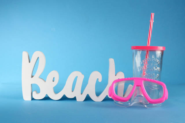 Beach text with diving mask and drinking glass on blue background
