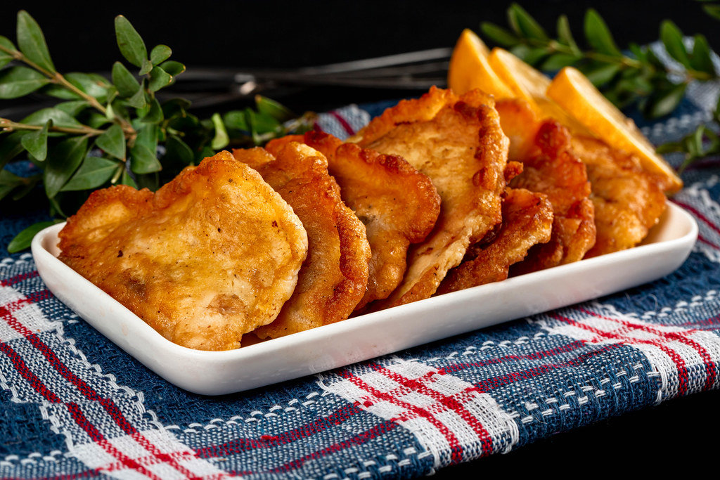 Fried fish slices in batter on a blue kitchen towel
