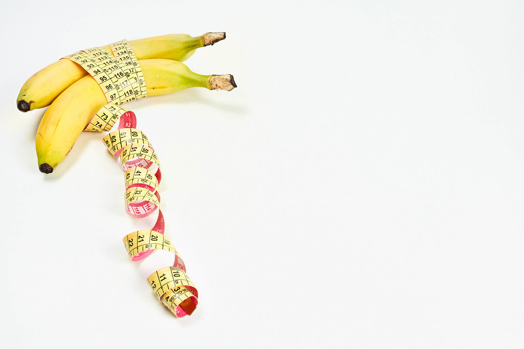 Measuring tape wrapped around bananas. Concept of penis enlargement, healthy eating, dieting and weight loss