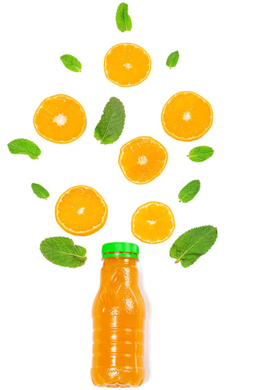 Orange juice bottle with mint leaves and orange slices on white, top view