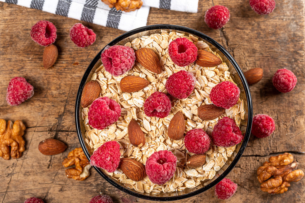 Oatmeal with raspberries and almonds on a wooden background, top view