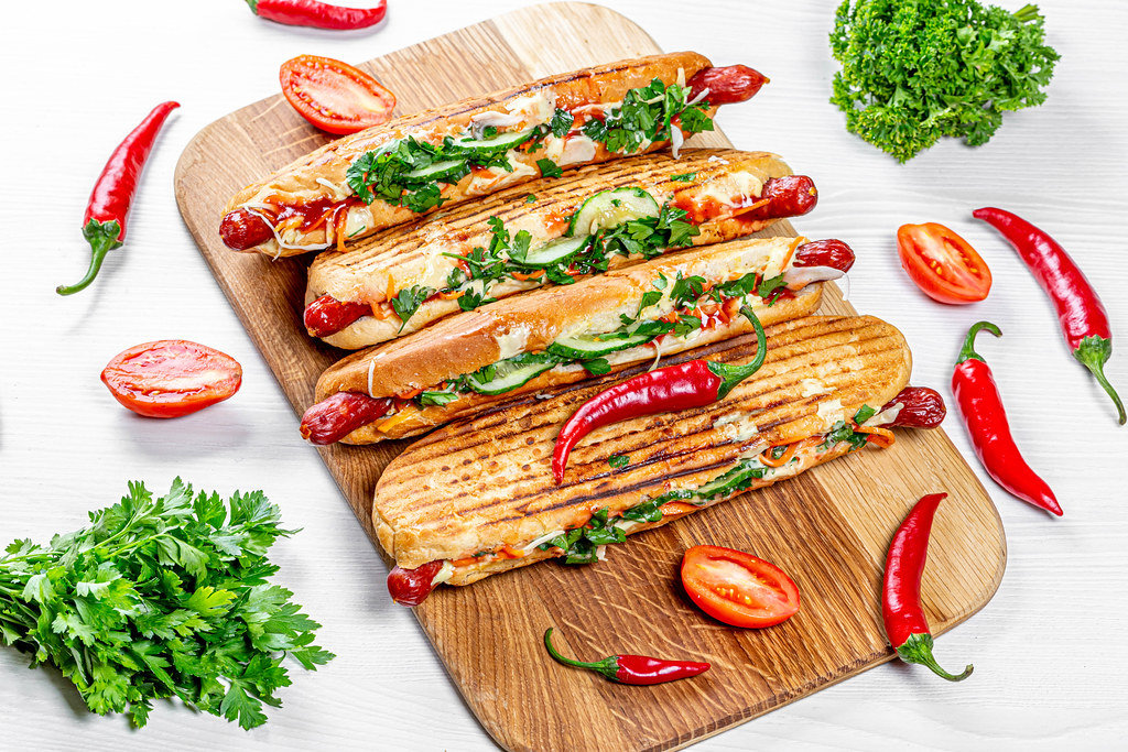 Grilled hot dogs with fresh vegetables, herbs and chili peppers