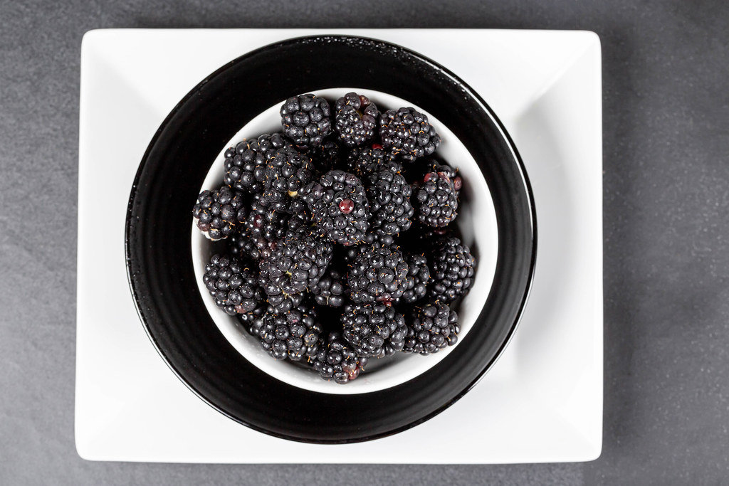 Blackberries in bowls on a dark background, top view