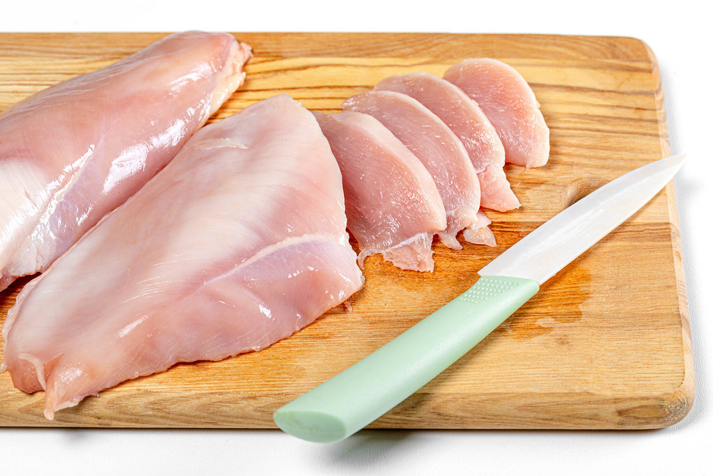 Raw chicken fillet on wooden kitchen board with knife