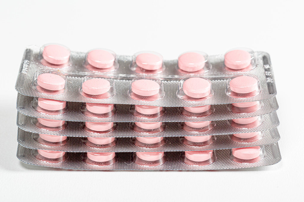 A stack of pink tablets in blisters. Drug treatment concept
