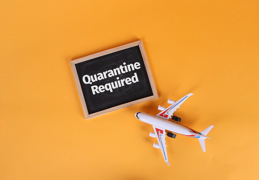 Airplane and blackboard with Quarantine Required text on orange background