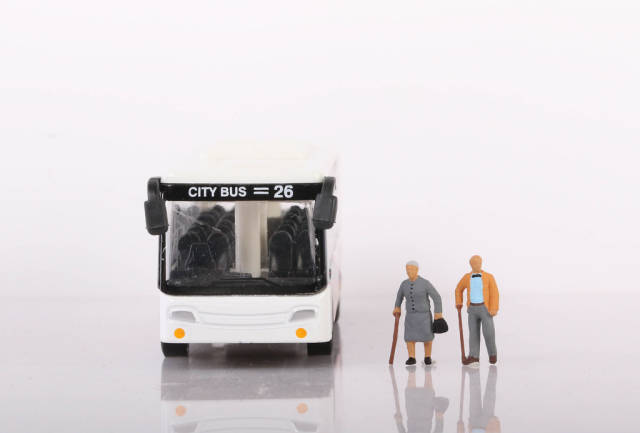 Senior couple with bus on white background
