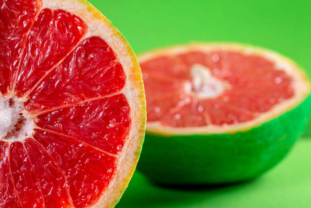 Bright summer fruit background with grapefruit halves on green backdrop