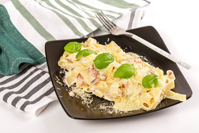 Tasty carbonara pasta with bacon and basil, traditional Italian cuisine