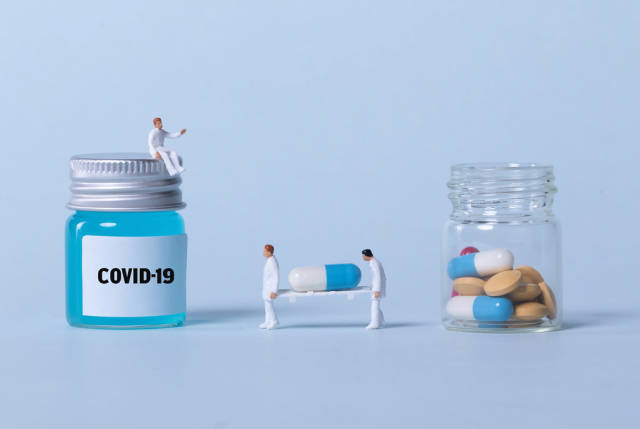 Medical workers with Covid-19 vaccine and glass full of pills