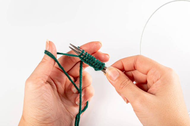 Woman dials loops with knitting needles and yarn