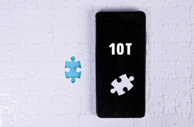 A modern big smartphone with a touch screen lies on a white jigsaw puzzle with 10T text