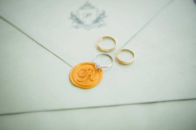 Trauringe und Verlobungsring auf mit Siegel verschlossener Hochzeitseinladung