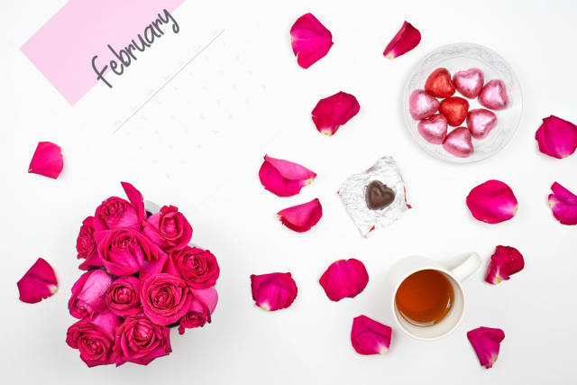 Beautiful rose flower petals, heart shape sweet chocolates and February calendar