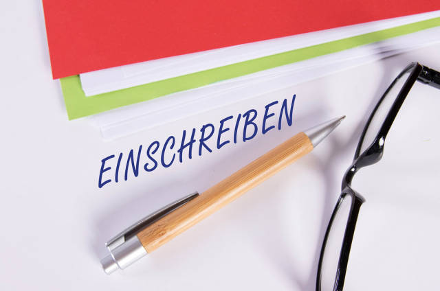 Stack of papers with pen, glasses and Einschreiben text