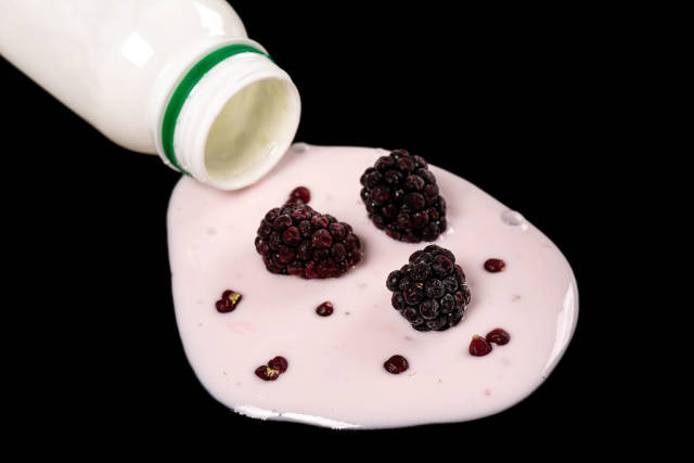 Close-up of spilled blackberry yogurt on dark background