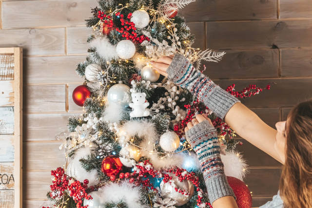 Holiday background, a girl decorating a christmas tree in the living room